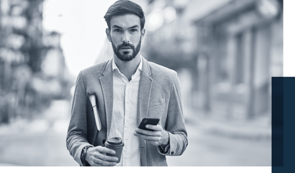 Stunned man looking forward holding his phone in one hand and his coffee cup and file folders in another