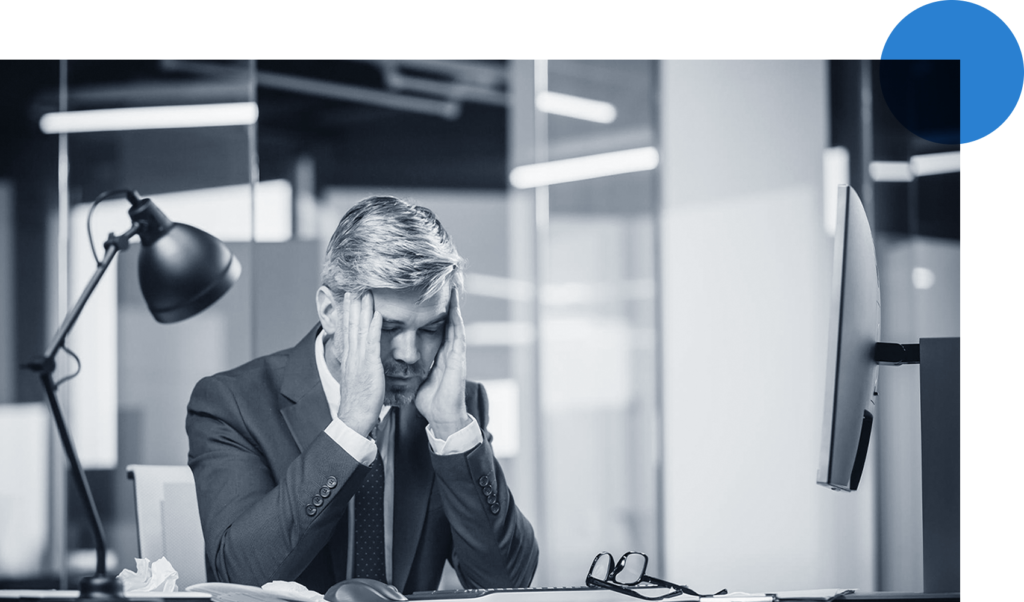 Stressed executive seated at his desk holding his head in his hands