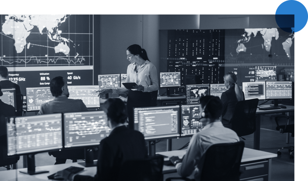 Security operations command center with analysts seated in front of multiple monitors and one large screen at the front of the room