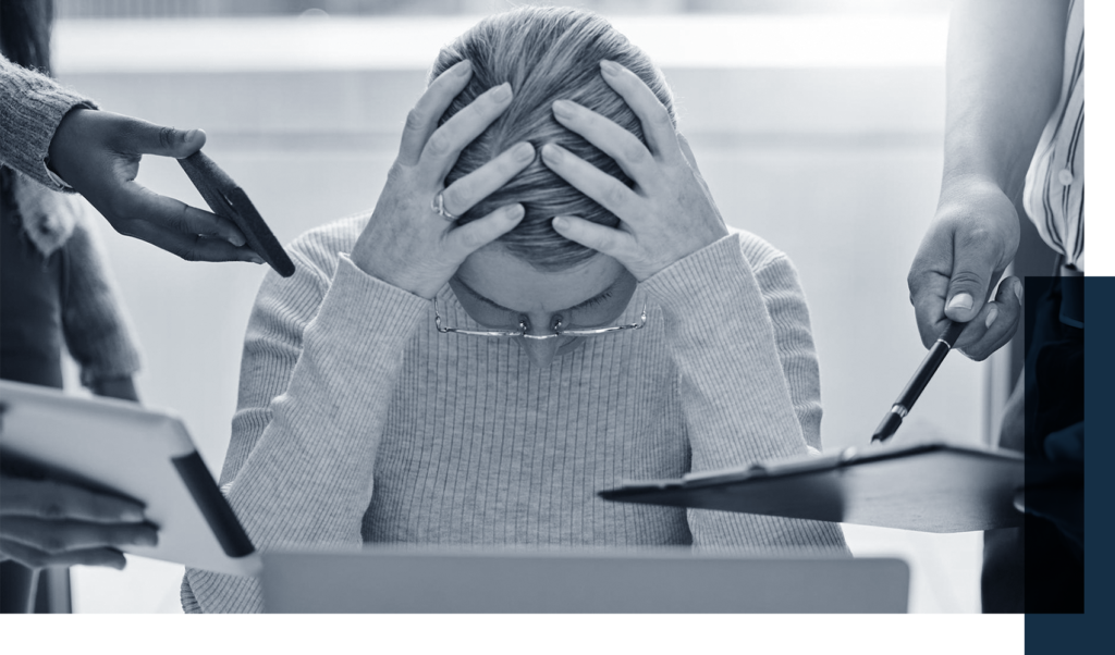 Stressed seated executive holding her head in hands looking down with hands coming in holding files, tablets, phones, and more coming in from both sides